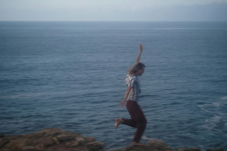 a woman jumping high into the air above the ocean