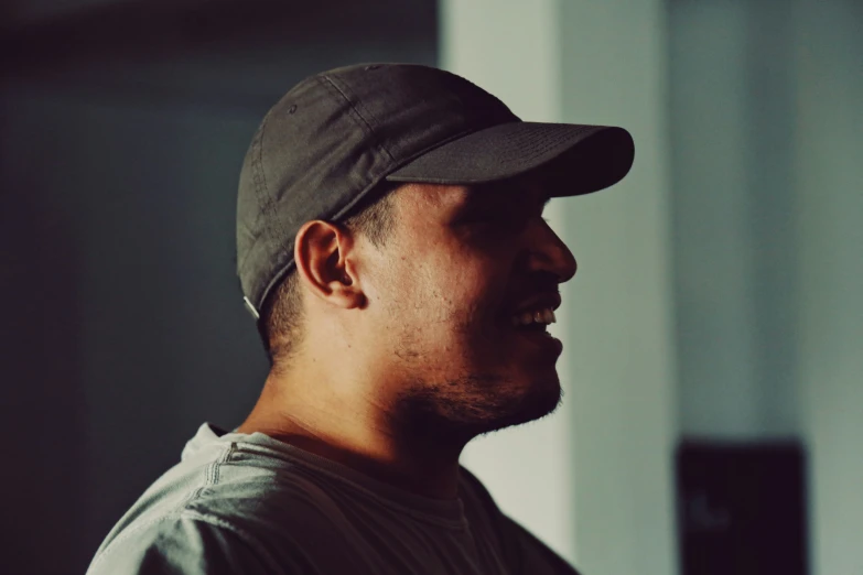 man wearing baseball hat in dimly lit room