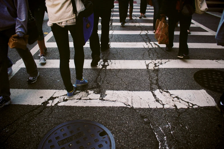 people are walking across a crosswalk on the street