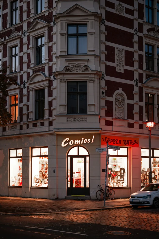 the lights in the store windows on the corner of a busy street