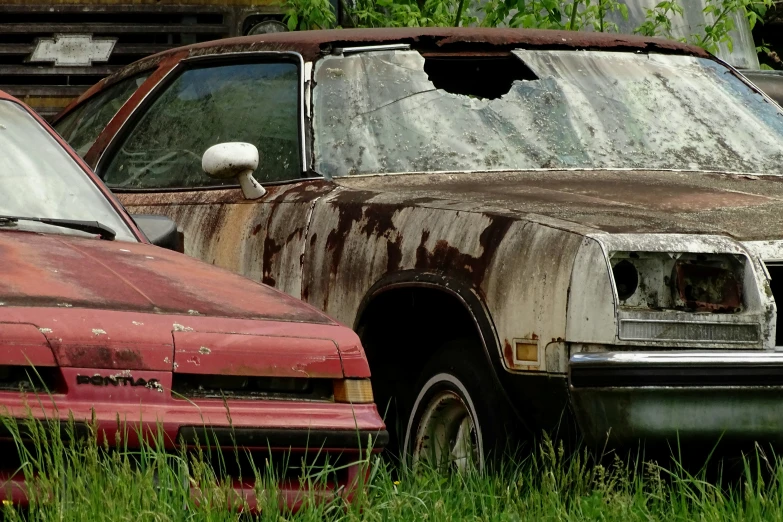 old rusted cars are sitting in the grass