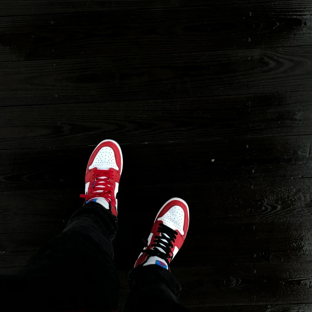 red and white vans sneakers sitting on a black wooden floor