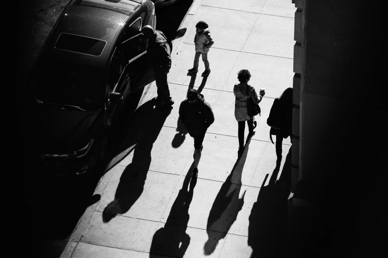 people walking on sidewalk with cars behind them