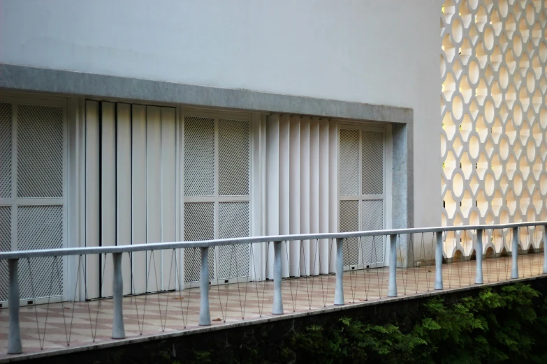 a metal fence is near a white building with shutters