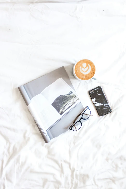 a coffee and a book sitting on top of a bed