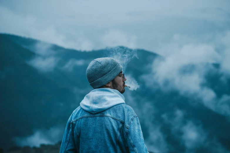 a person is smoking a cigarette near a mountain