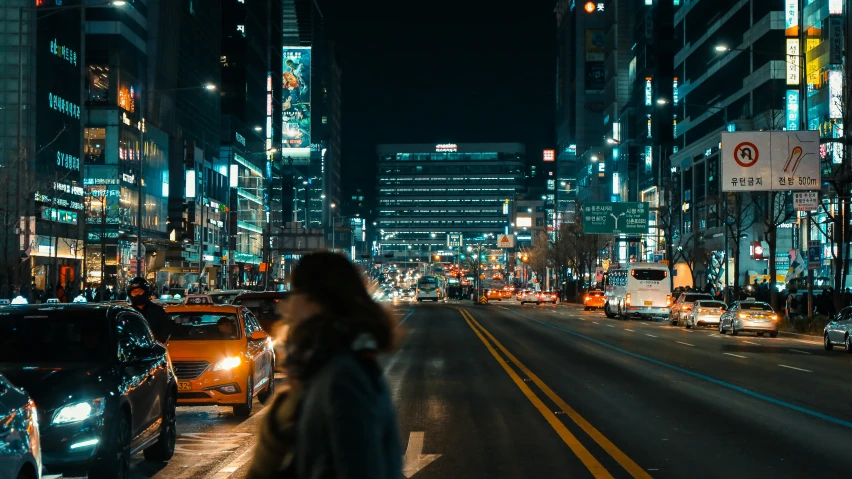 a busy city street with people walking along it at night