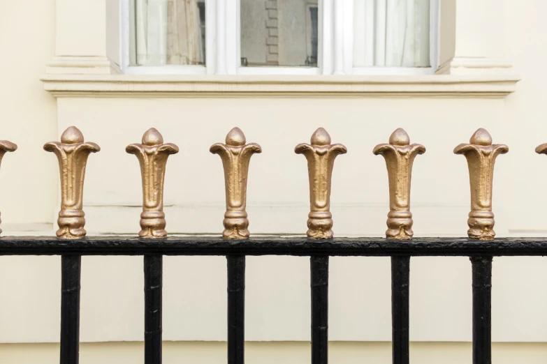 a long black metal fence has gold designs on it