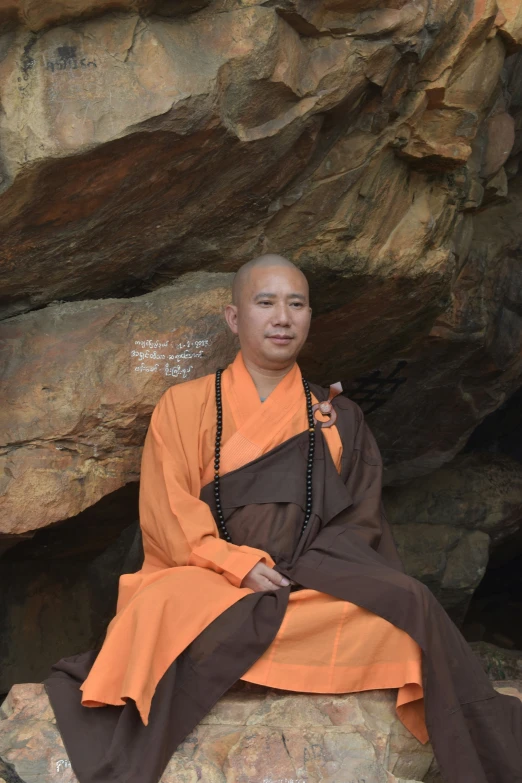 man dressed in costume sitting on rock next to rock formation