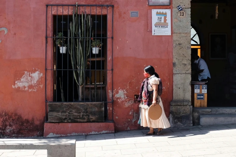 a person walking past a pink building with metal gates