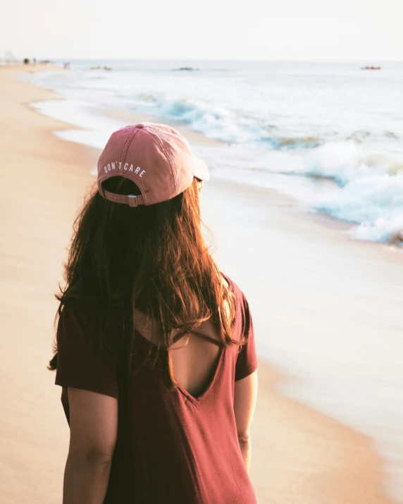 a woman standing on the beach looking at the waves