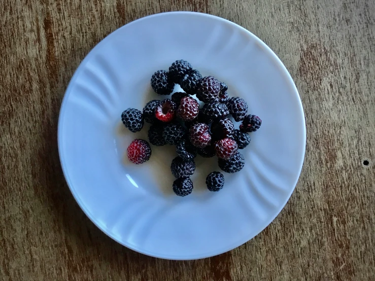 there is a white plate filled with berry salad