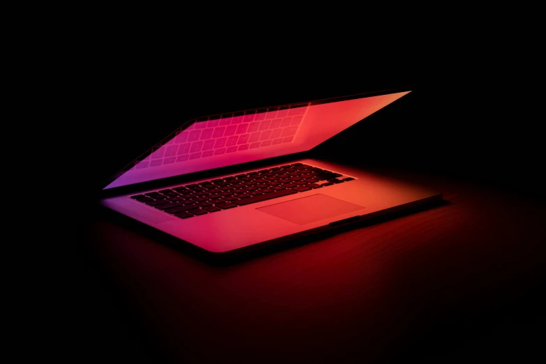 an open laptop on a desk lit up with a neon color