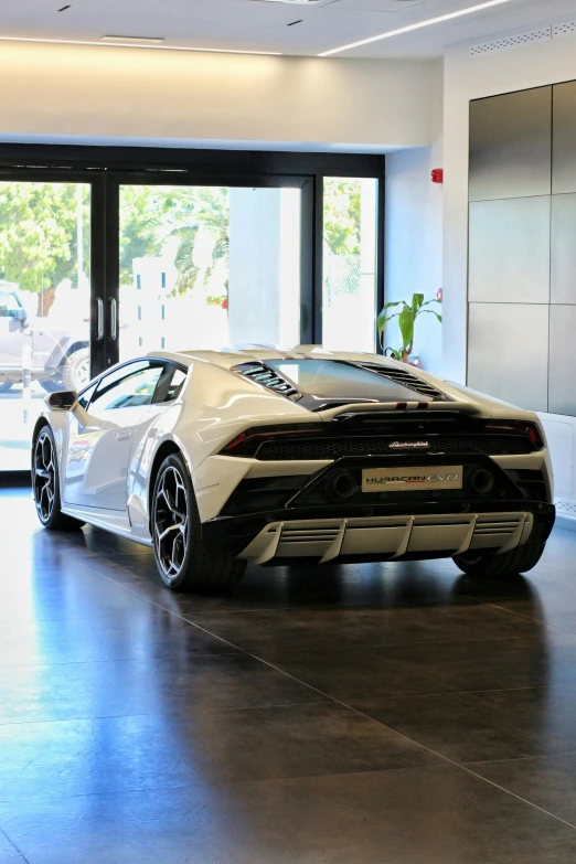 a white lamb - like vehicle parked in front of a glass building