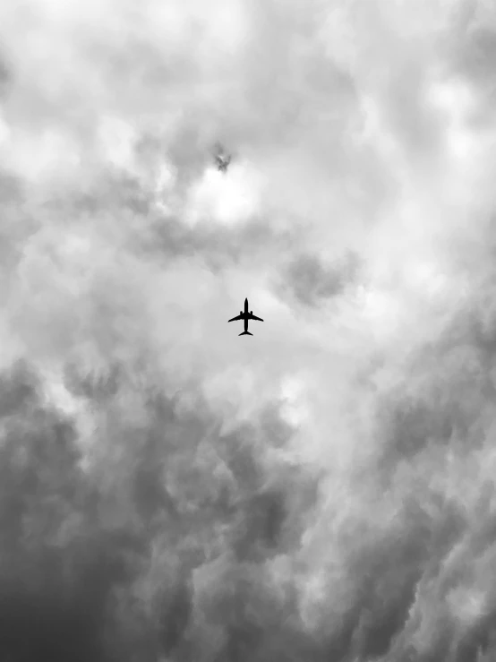 a plane flies high in the cloudy sky