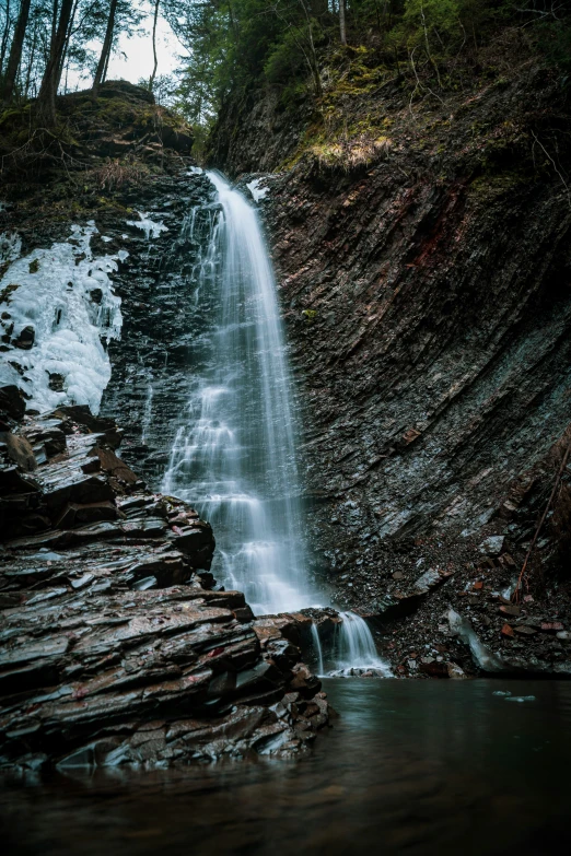 the water fall is at the base of a steep cliff