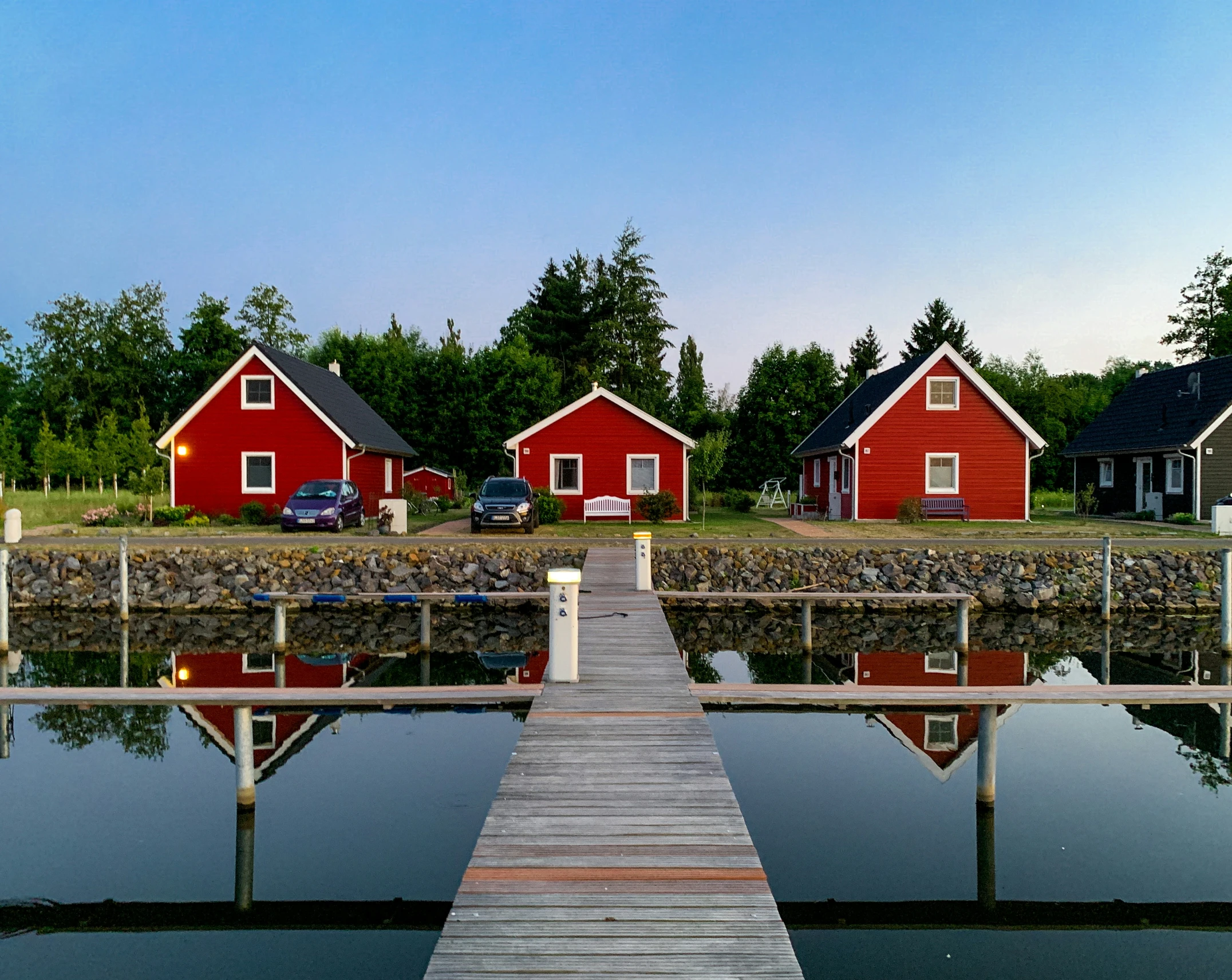 a dock sits next to two houses on a quiet lake