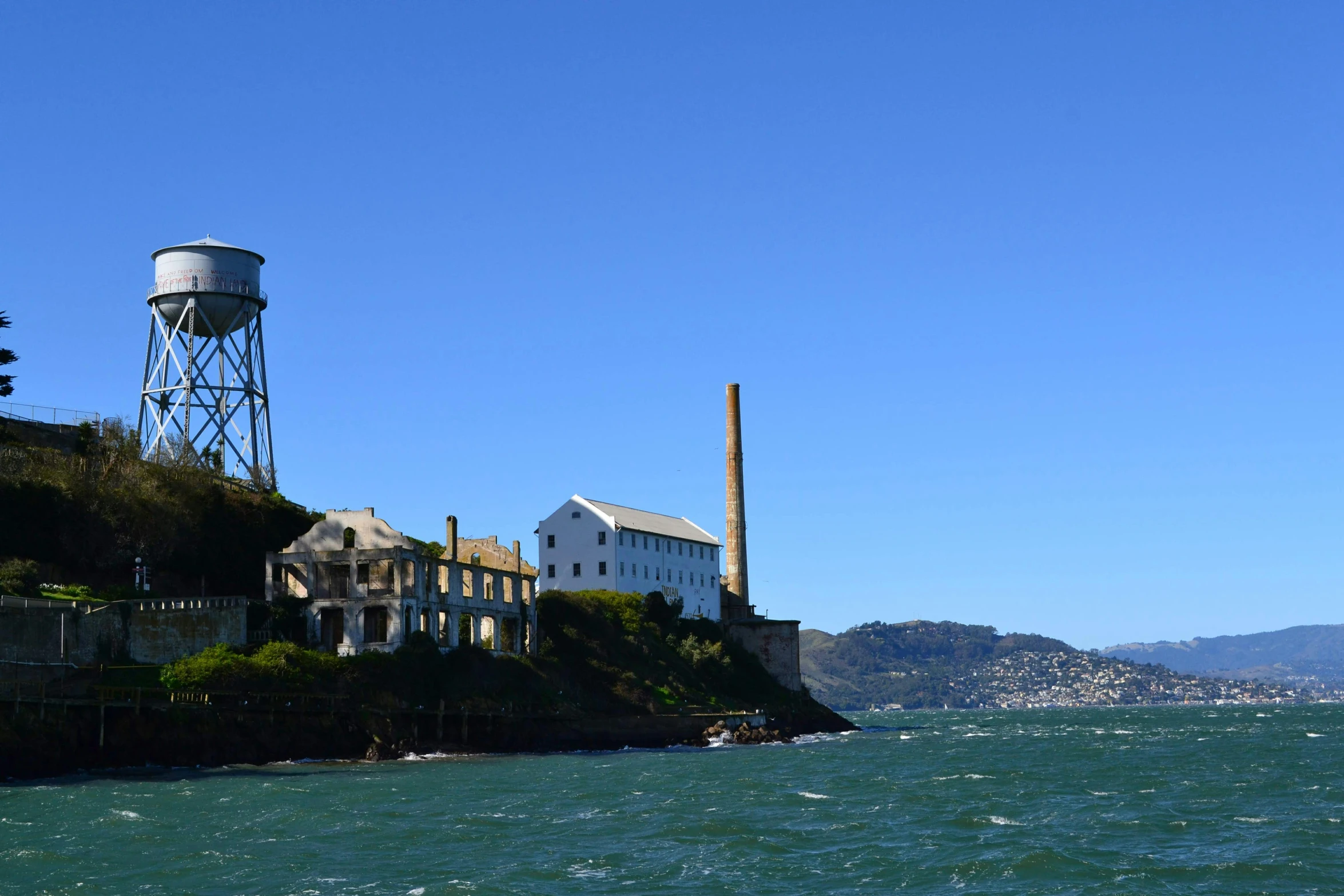 an old water tower is built on a cliff beside the water