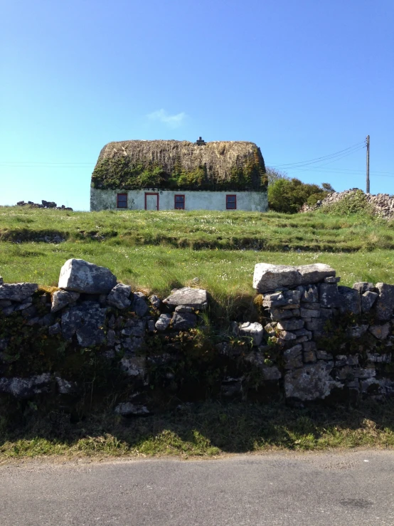 an old farm house covered with grass in the background