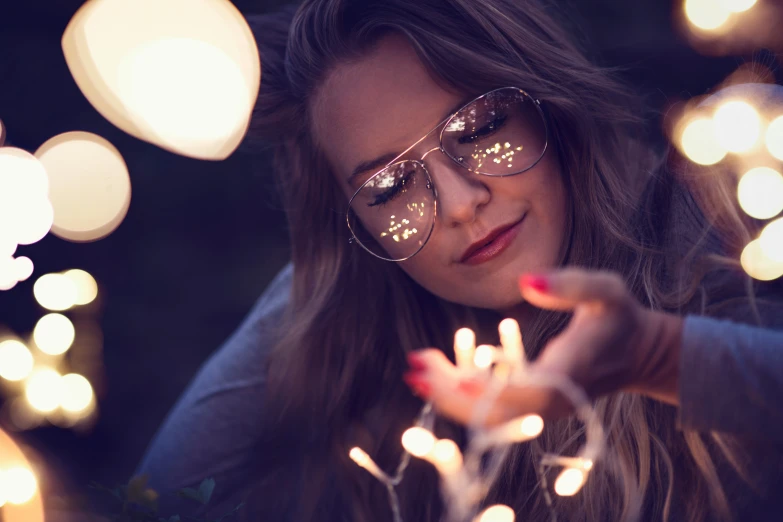 young woman in glasses with string of lights