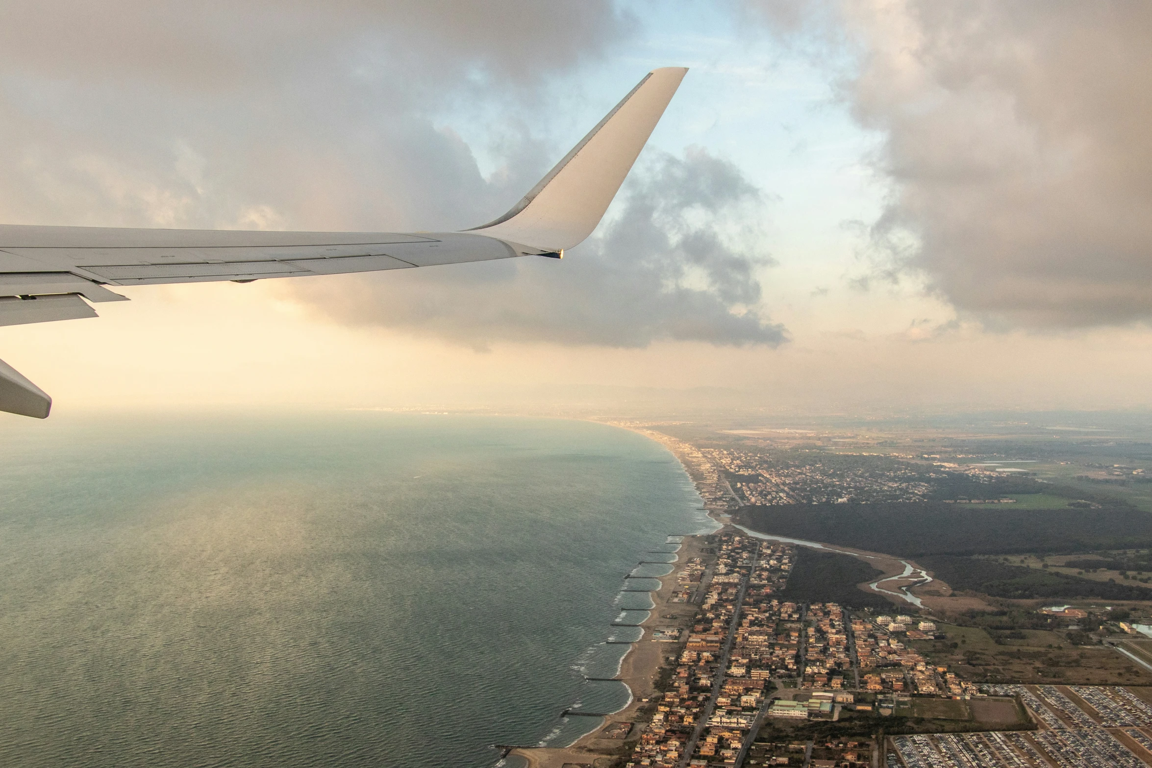 an airplane wing is shown above the city and sea