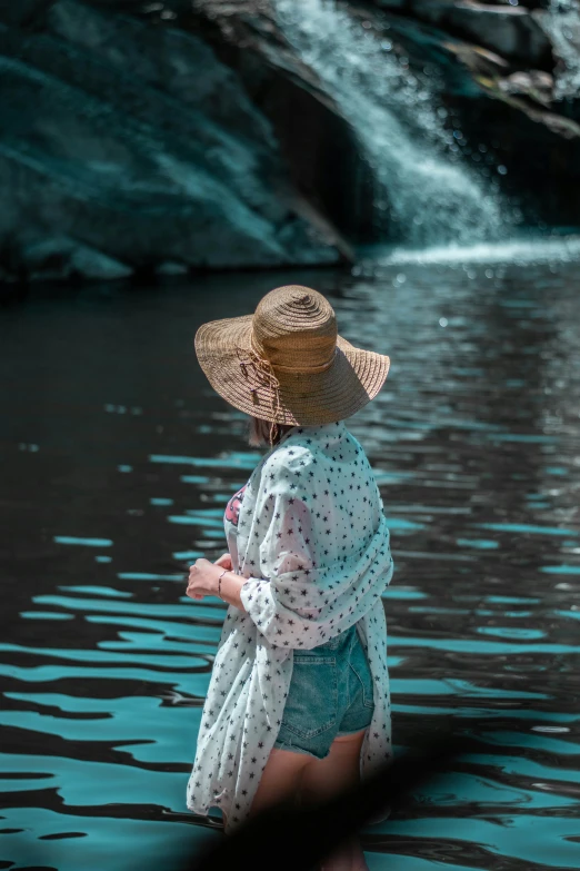 a woman in a straw hat standing near the river