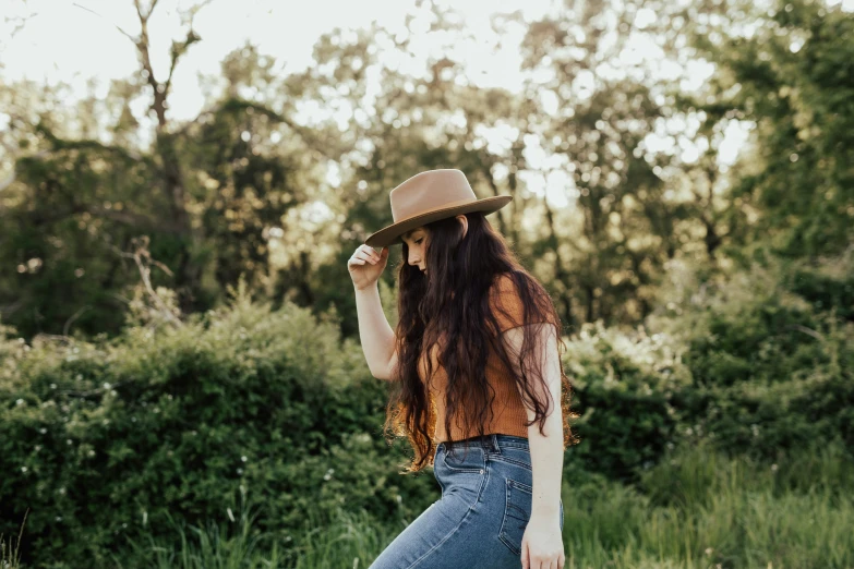 a woman in jeans is standing by a bush