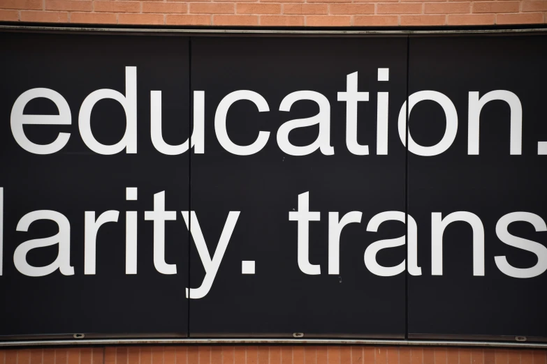 an educational charity trans sign placed on a brick building
