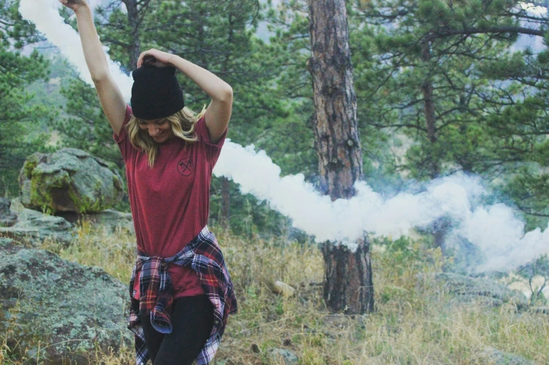 woman in the woods throwing rocks while smoking soing