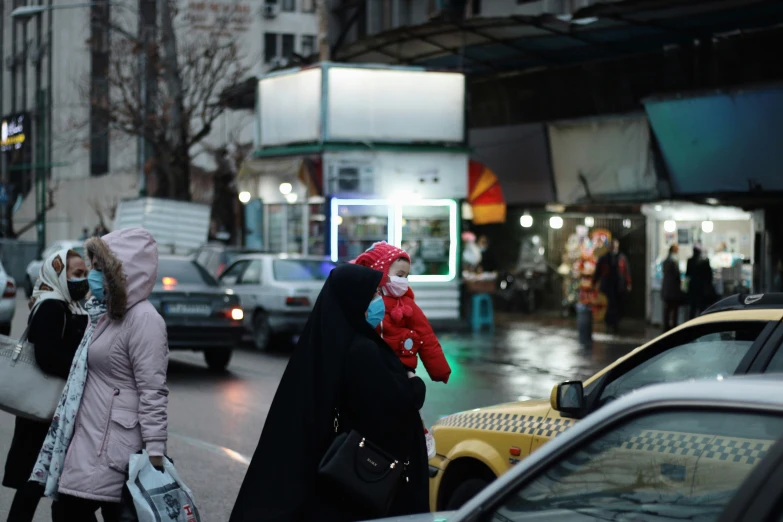 two women walking down the street with many cars and people standing outside