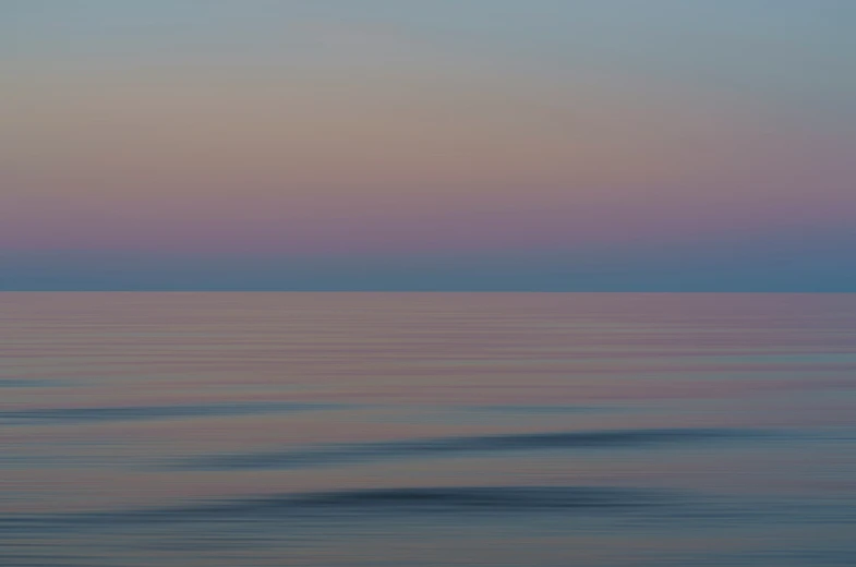 a surfer is in the ocean at dusk