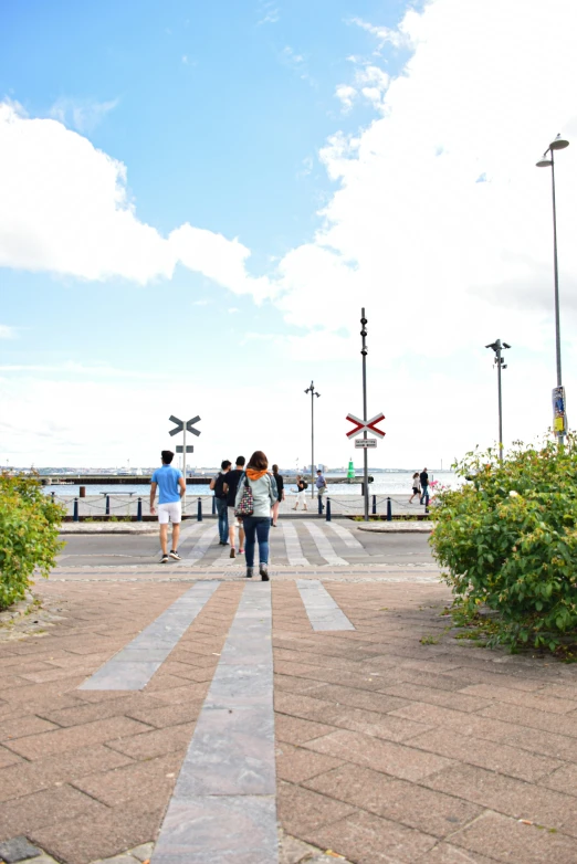 three people walking down a brick pathway toward a water view