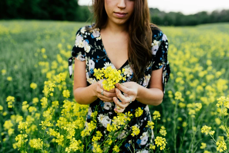 a woman is standing in the middle of a field with a flower