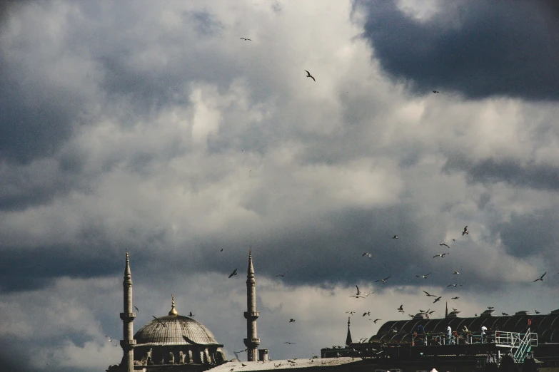 the birds fly in the clouds over a building