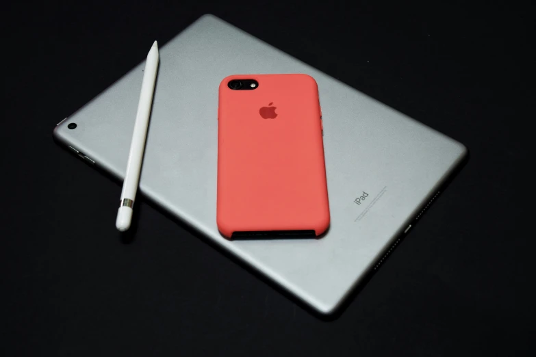 a red iphone case sitting next to an apple pencil on a table