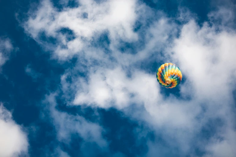 a balloon flying through the air, in between clouds