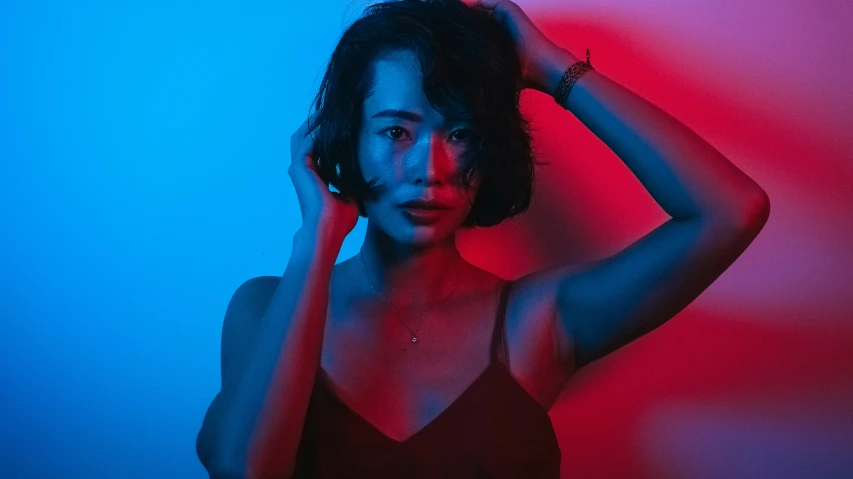 woman posing in dark clothing against neon blue and red background