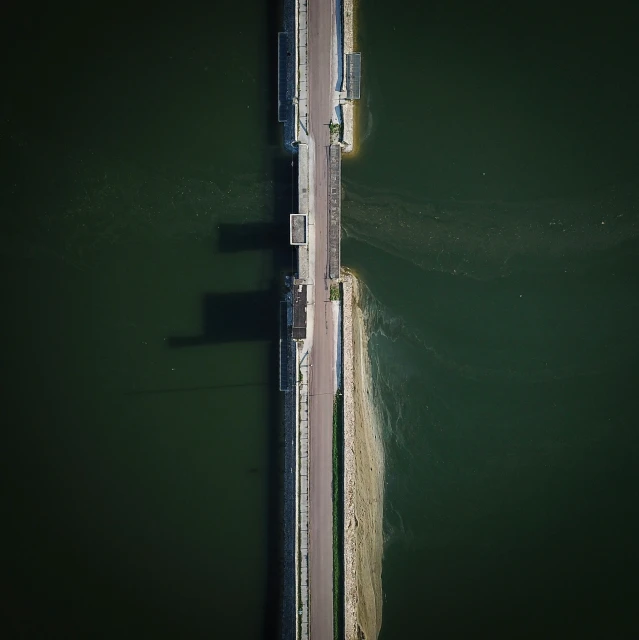 two people stand at the end of a bridge looking out onto the water