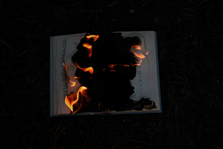 fire in the middle of a notebook on a ground