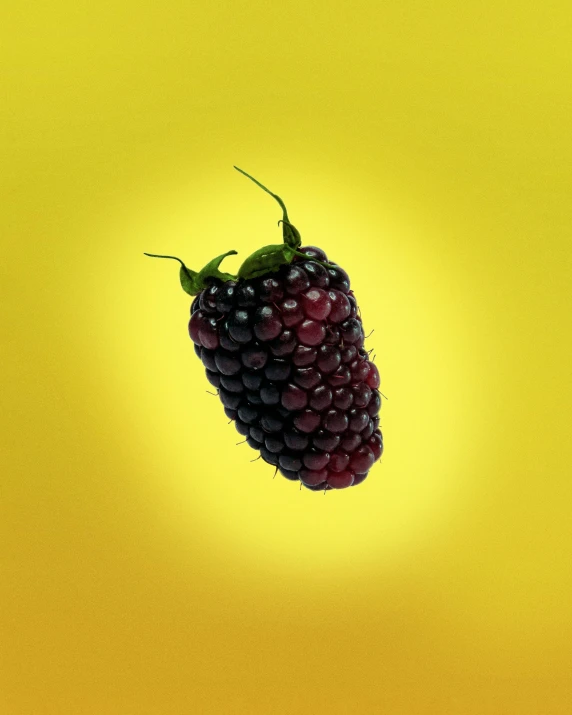 a raspberry is suspended in mid air with a yellow background