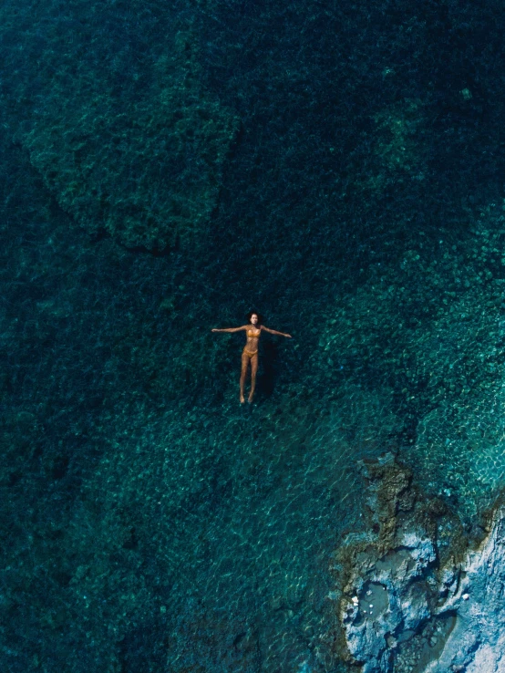 man in deep blue water alone with his arms outstretched