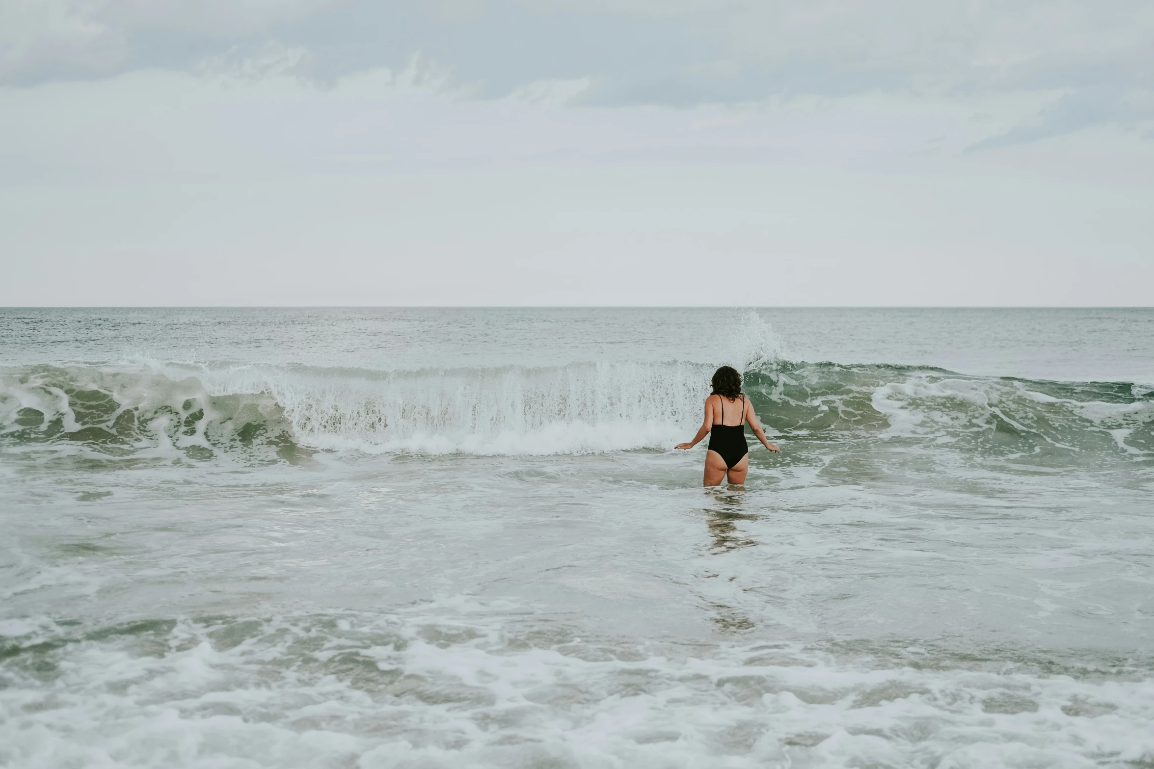 a woman standing in the water next to the shore