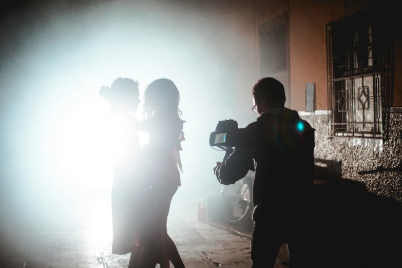 two people standing on a street with lights behind them