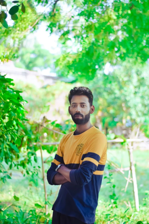 a man in a yellow and black shirt is standing next to a tree