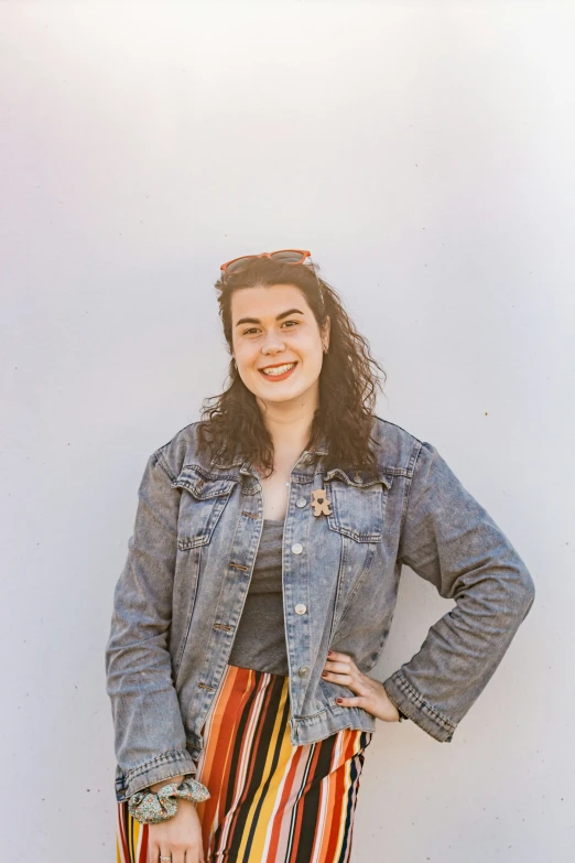 a woman with long curly hair standing in front of a wall