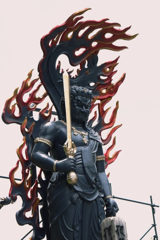 a statue standing outside with many fire blazing around it