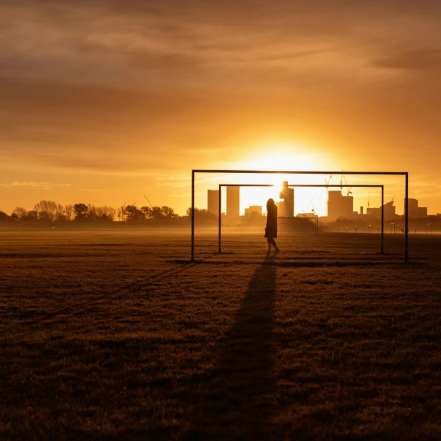 two people stand in a field as the sun goes down