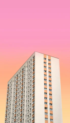 a tall, white building against a pink and orange sky