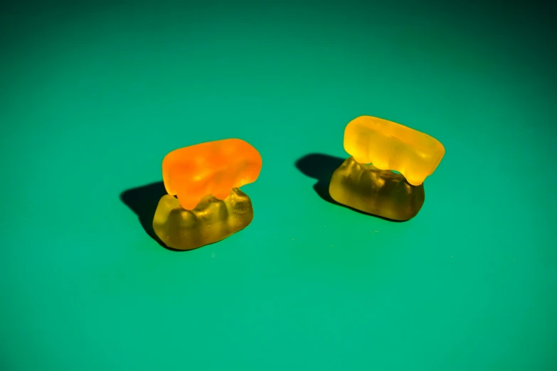 two gummy bears in front of a green surface