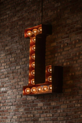 light bulb letter on brick wall with wall sconce